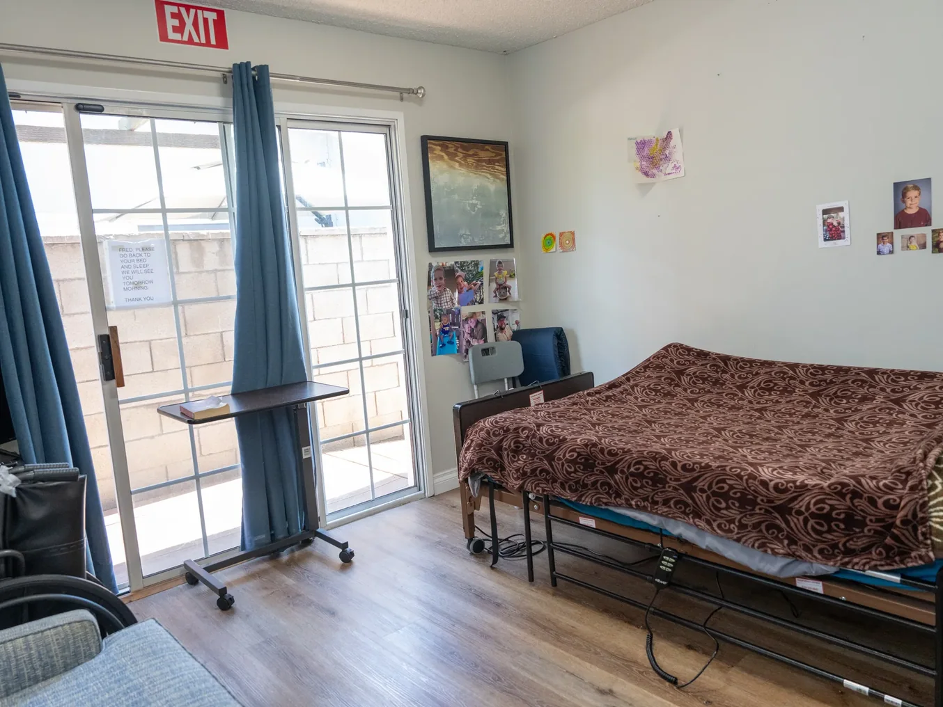 Accessible resident bedroom with adjustable hospital bed and sliding glass door to patio