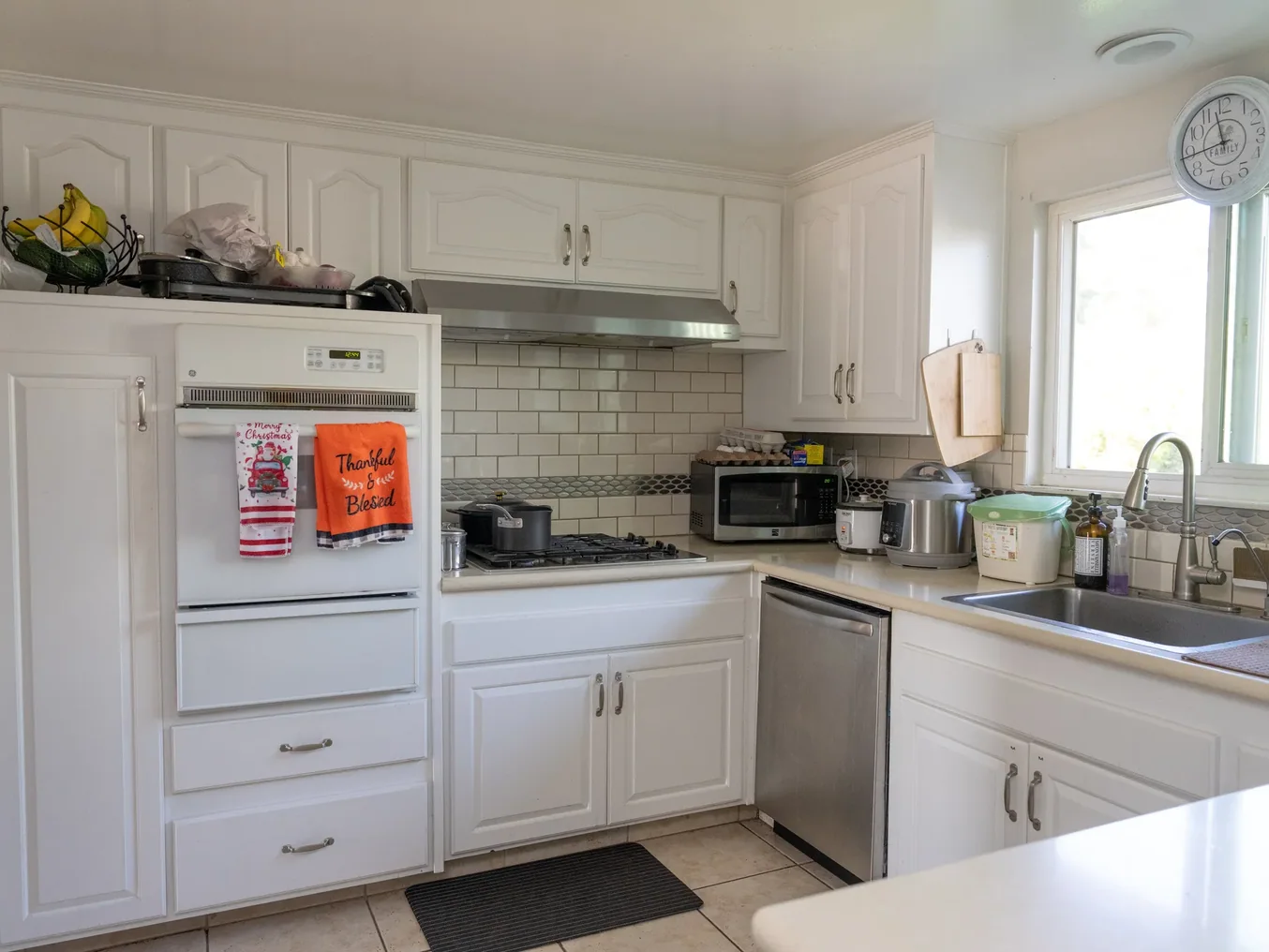 Spacious accessible kitchen with white cabinetry and subway tile backsplash