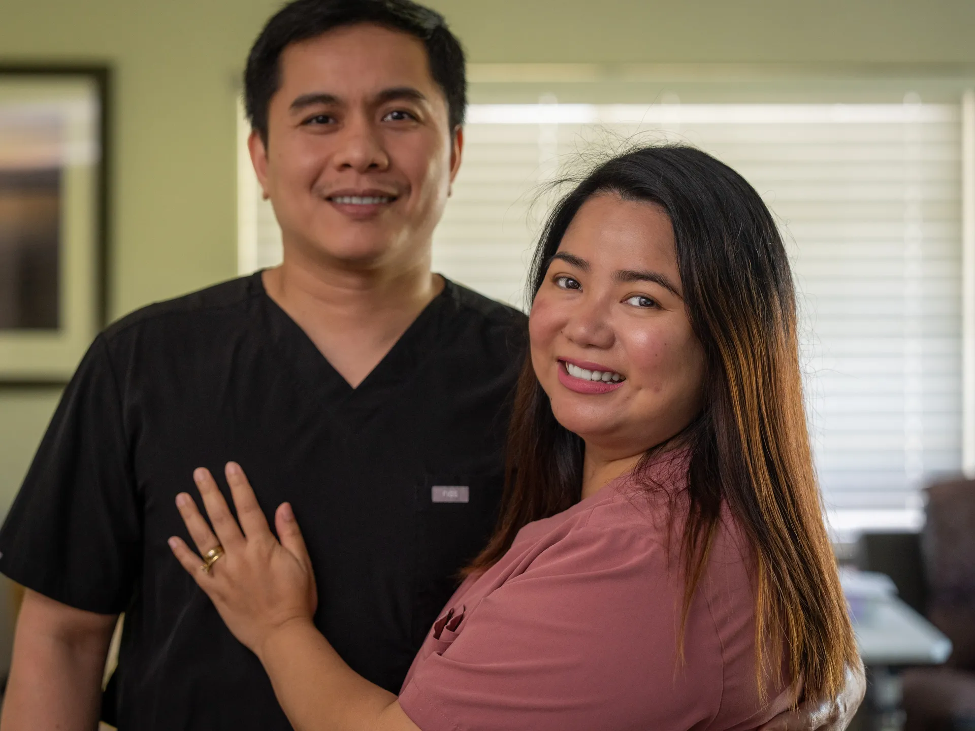 Two smiling healthcare professionals in a warm, welcoming clinical office environment